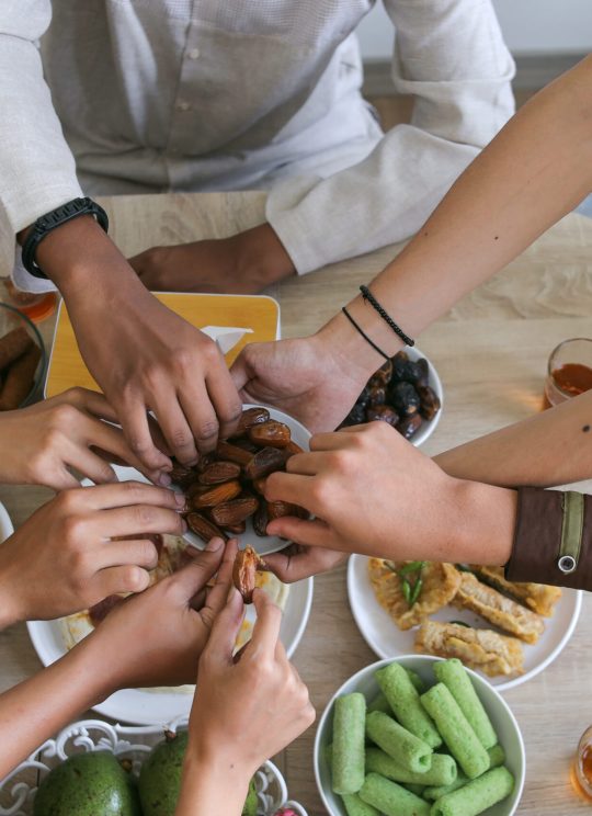 Top View of Muslim Friends Sharing a Bowl of Dates While Enjoying Iftar Dinner Together During Ramadan Feast at Dining Table